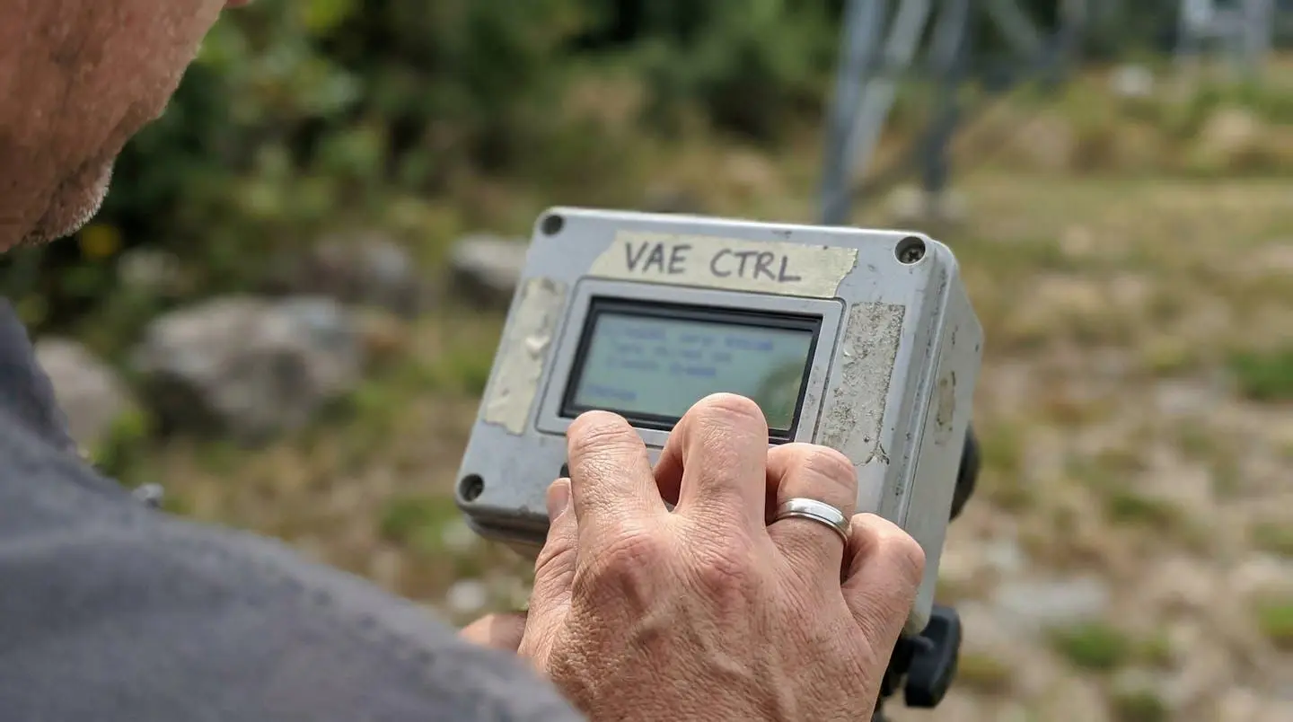 Gros plan sur la main d'un cycliste posée près d'un écran de contrôle de VAE, écran volontairement flouté, lumière naturelle extérieure
